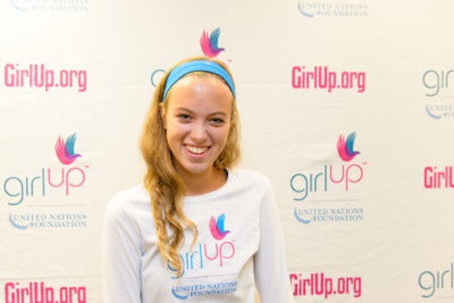 Amanda Hart_2013-2014 Teen Advisor (close angle headshot, a picture little blurry ) a teen girl wearing her girl up white shirt with her smiley face facing the camera, and background is girlup.org board