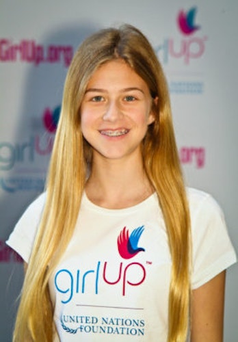 Annie Gersh 2011-2012 Class Teen Advisors (close angle headshot, a picture little blurry ) a teen girl wearing her girl up white shirt with her smiley face facing the camera, and background is girlup.org board