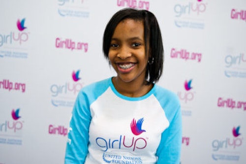 Bridget Duru_The founding class of Teen Advisors(close angle, but not clear picture headshot ) a teen girl wearing her girl up blue long shirt with her smiley face facing the camera, and background is girlup.org board