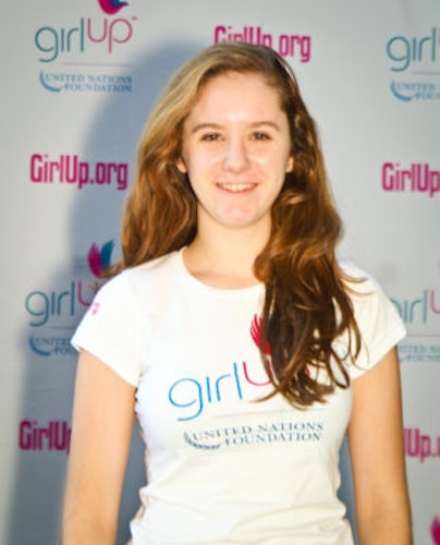 Charlotte May_ Hometown: Bronxville, NY._2011-2012 Class The second class of Teen Advisors (close angle headshot) a teen girl wearing her girl up white shirt with her smiley face facing the camera, and background is girlup.org board