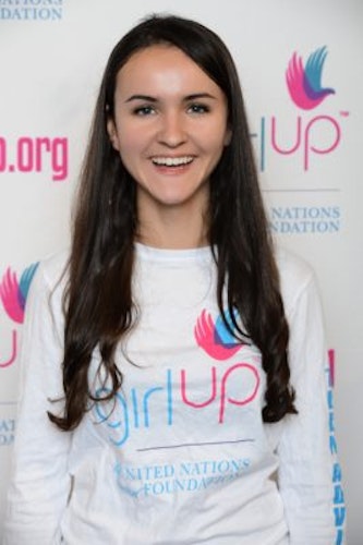 Claire Brito, Co-Chair_ 2015-2016 Teen Advisors(close angle headshot )wearing her girl up white shirt with her smiley face facing the camera, and background is girlup.org board