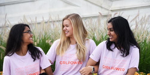 3 jeunes filles d’ethnies différentes portant son maillot rose « Girl Power », souriant et se regardant