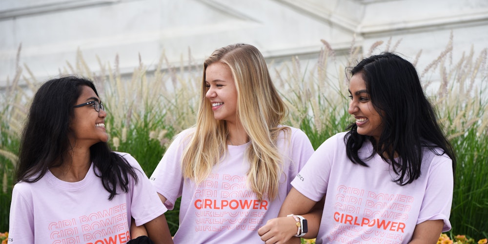 3 different ethnic girls wearing pink girl power t-shirt and smile and looking at each other