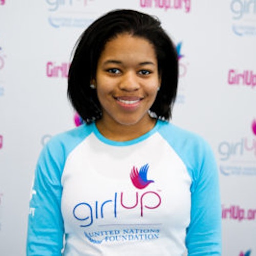 Erica Lamberson_首届青年顾问（近距离头像照，画面不清晰），照片中的她穿着蓝色 Girl Up 长袖 T 恤，面对镜头微笑，照片背景为 girlup.org 活动展板