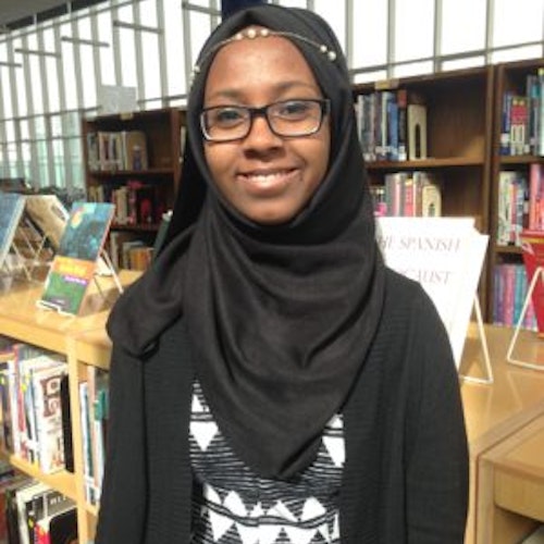 Faatimah Solomon_2016-2017 届青年顾问（近距离半身照），照片背景为图书馆，照片中的她戴着黑色头巾
