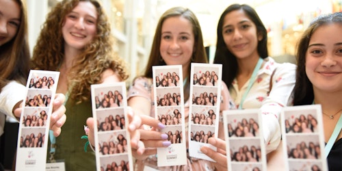 5 meninas segurando as suas fotografias da cabine fotográfica na Conferência de Liderança