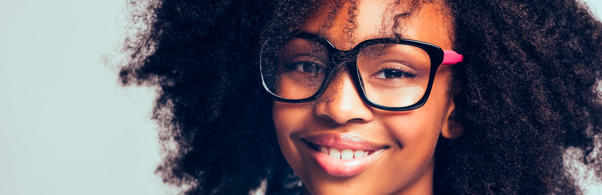 (close cutoff shot) a girl with big glasses on and a big smile