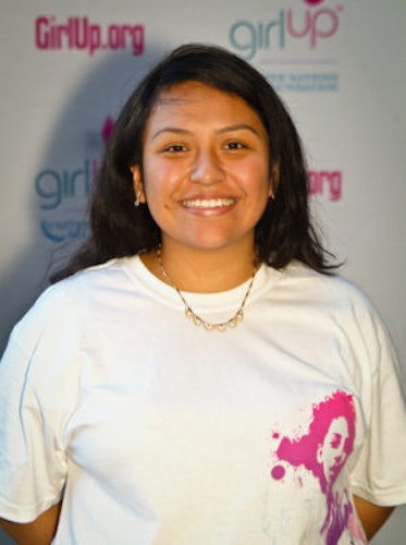 Itzel Delgado, Co-Chair_Hometown: New York, NY_2011-2012 Class The second class of Teen Advisors (close angle headshot) a teen girl wearing her girl up white shirt with her smiley face facing the camera, and background is girlup.org board