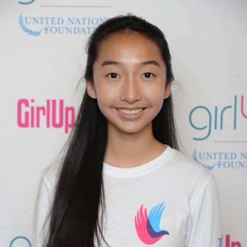 Janet Ho_Consejeras adolescentes 2014-2015 (retrato en primer plano); una adolescente con la camiseta blanca de Girl Up, sonriendo a la cámara, con el cartel de girlup.org de fondo.