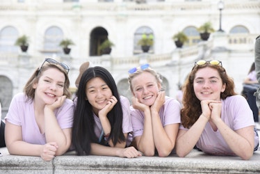 4 Girl Up girls with a different ethnic group holding their head and laying in front of the capitol in DC