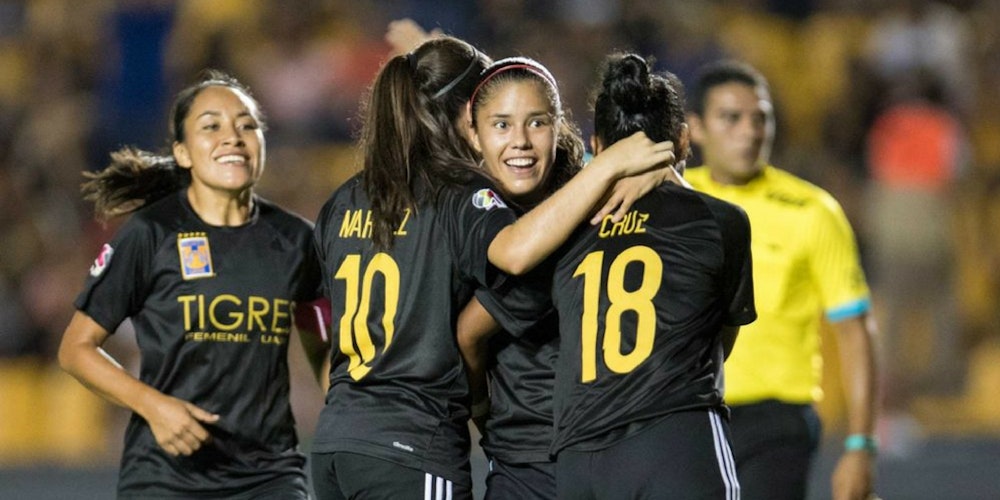 4 women on the picture _women soccer team tigres Mexico teammates are happily giving each other group hug on the filed
