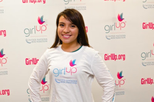 Martha Zuniga Hometown: Chicago, IL_2012-2013 Class Teen Advisors (close angle headshot, a little blurry picture ) a teen girl wearing her girl up white shirt with her smiley face facing the camera, and background is girlup.org board
