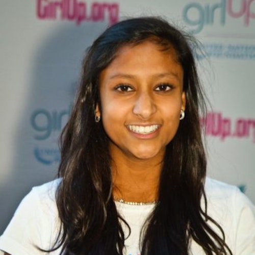 Priyanka Jain_家乡： 美国华盛顿州贝尔维尤_2011-2012 届（即第二届）青年顾问（近距离头像照），照片中的她穿着白色 Girl Up T 恤，面对镜头微笑，照片背景为 girlup.org 活动展板