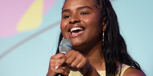 (close head shot)a girl is holding a mic on her right hand and her left hand finger point down and speaking