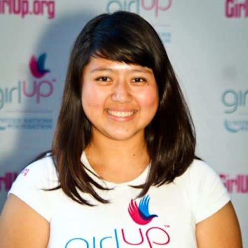 Rocio Ortega_家乡： 美国加利福尼亚州洛杉矶_2011-2012 届（即第二届）青年顾问（近距离头像照），照片中的她穿着白色 Girl Up T 恤，面对镜头微笑，照片背景为 girlup.org 活动展板