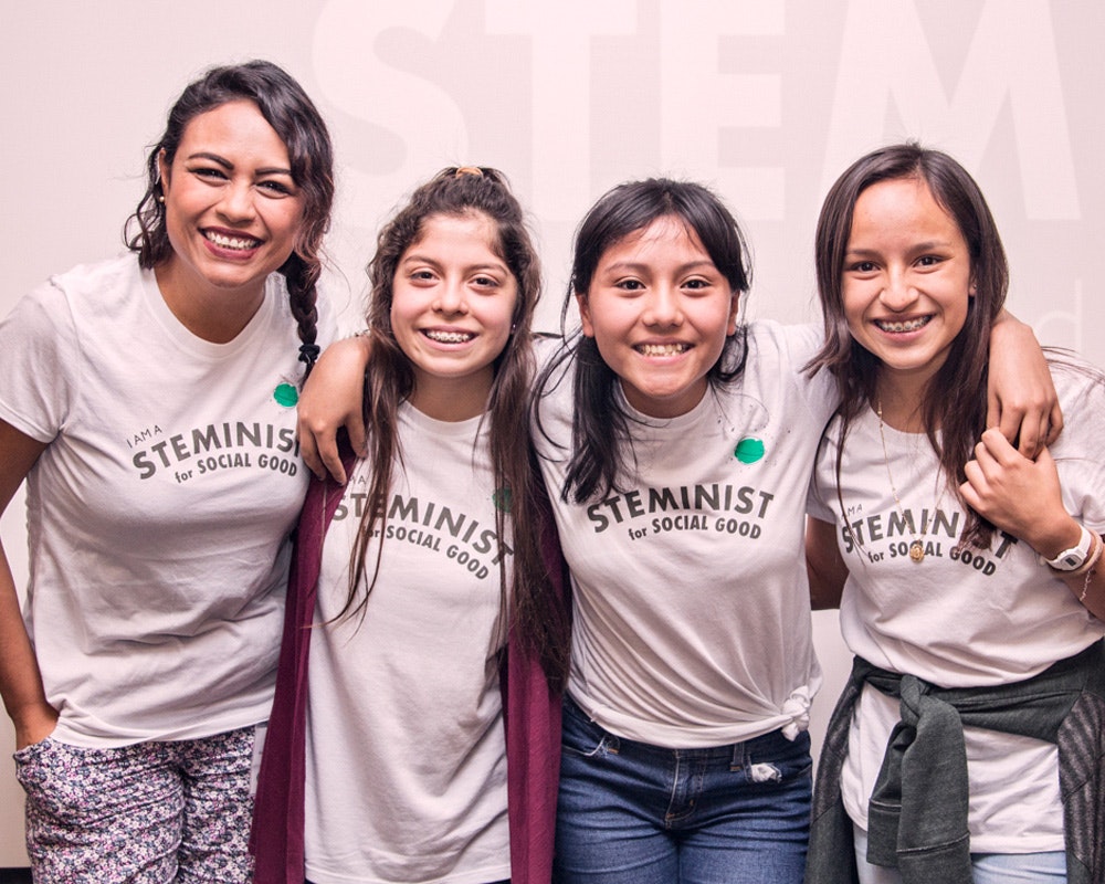 4 teen girls have their arm around each other wearing steminist t-shirt