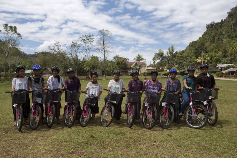 a group pictures with girls with a big smile on their face on their bicycle and helmet on