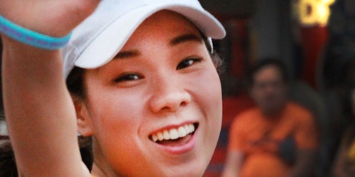 Primer plano de una chica con ropa de tenis sonriendo a la cámara.