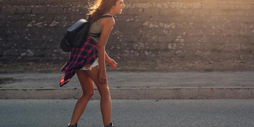(photo intégrale du corps) une fille sur son skateboard tout sourire, lumière du soleil en arrière-plan