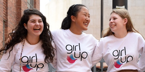 Cuatro chicas de Girl Up de diferentes etnias con camisetas de Girl Up (foto grupal) abrazadas.
