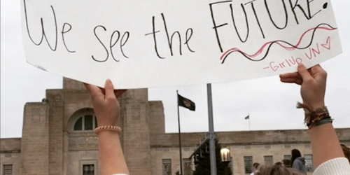 女性大游行中一名女孩举着牌子，上面写着： “你看到的是女孩，我们看到的是未来。”