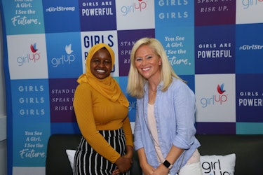 Munira Alimire taking picture with a speaker in front of the girl up borad