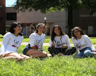 4 girls wearing teen advisers shirt sitting on the grass floor and laughing on the picture