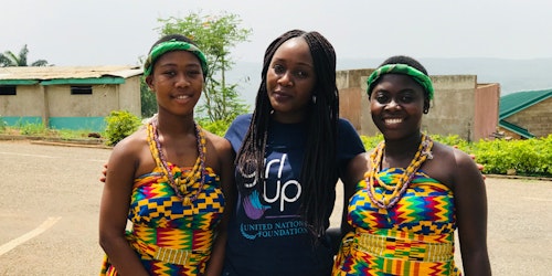 Duas integrantes africanas da Girl Up (usando roupas tradicionais do continente) com uma funcionária da Girl Up