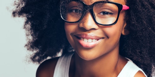 Foto em close de uma menina sorridente usando óculos grandes