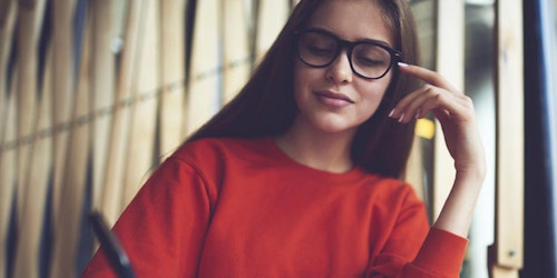 (lower angle) a girl wearing black glasses and writing on her note book