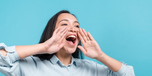 uma menina com suas duas mãos perto da boca com a boca aberta, com fundo azul