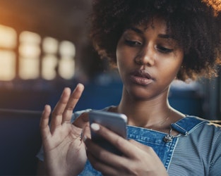a girl who is looking down and using her finger to scrolling the phone