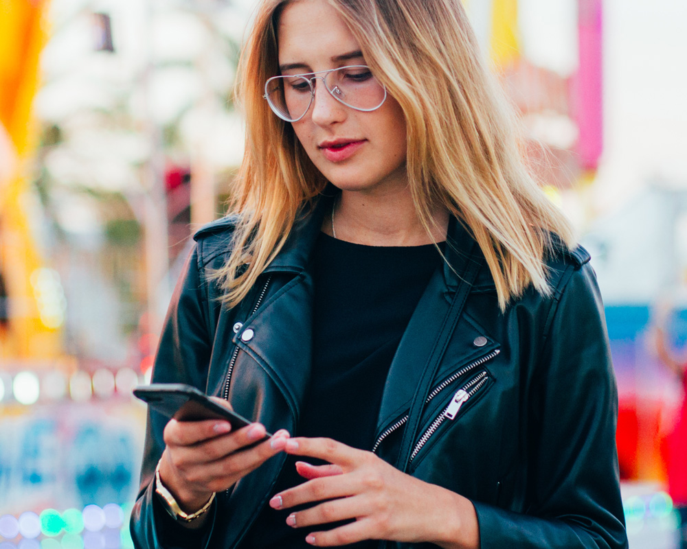 a phone is holding an iPhone and looking down at her phone