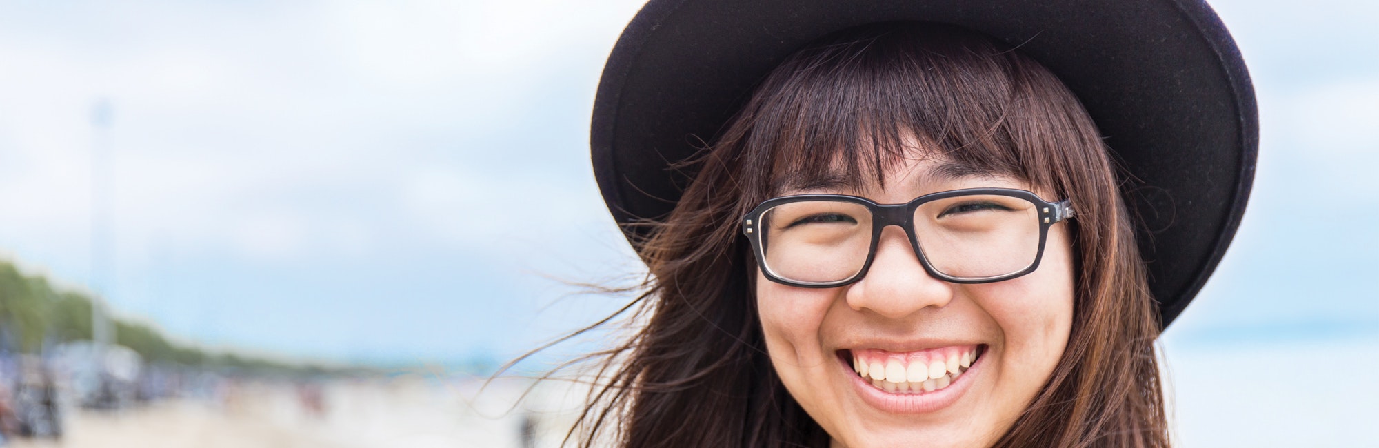 a close up shot of a girl with big smile and wear hat with glasses on