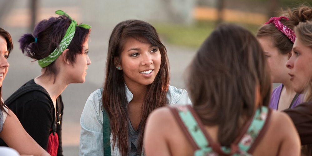 a group of girls talking in a circle, looking at each other (close shot)