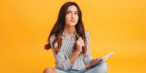 Menina segurando um lápis com uma das pontas encostada no queixo e olhando pensativa para cima
