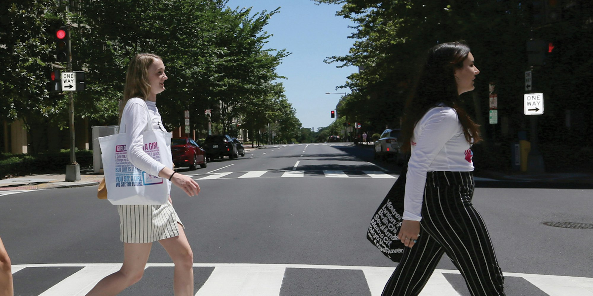 5 名女孩穿着青年顾问 T 恤，面朝前方一个接一个地过马路