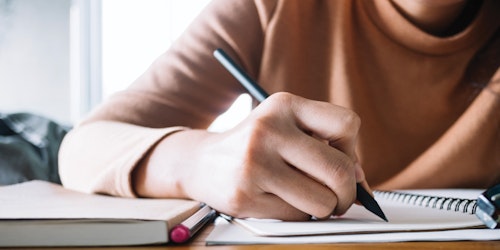 un plan rapproché d’une personne écrivant à l’aide d’un stylo sur un bloc-note