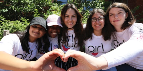 Cinco Consejeras adolescentes abrazadas haciendo la forma de un corazón con las manos.