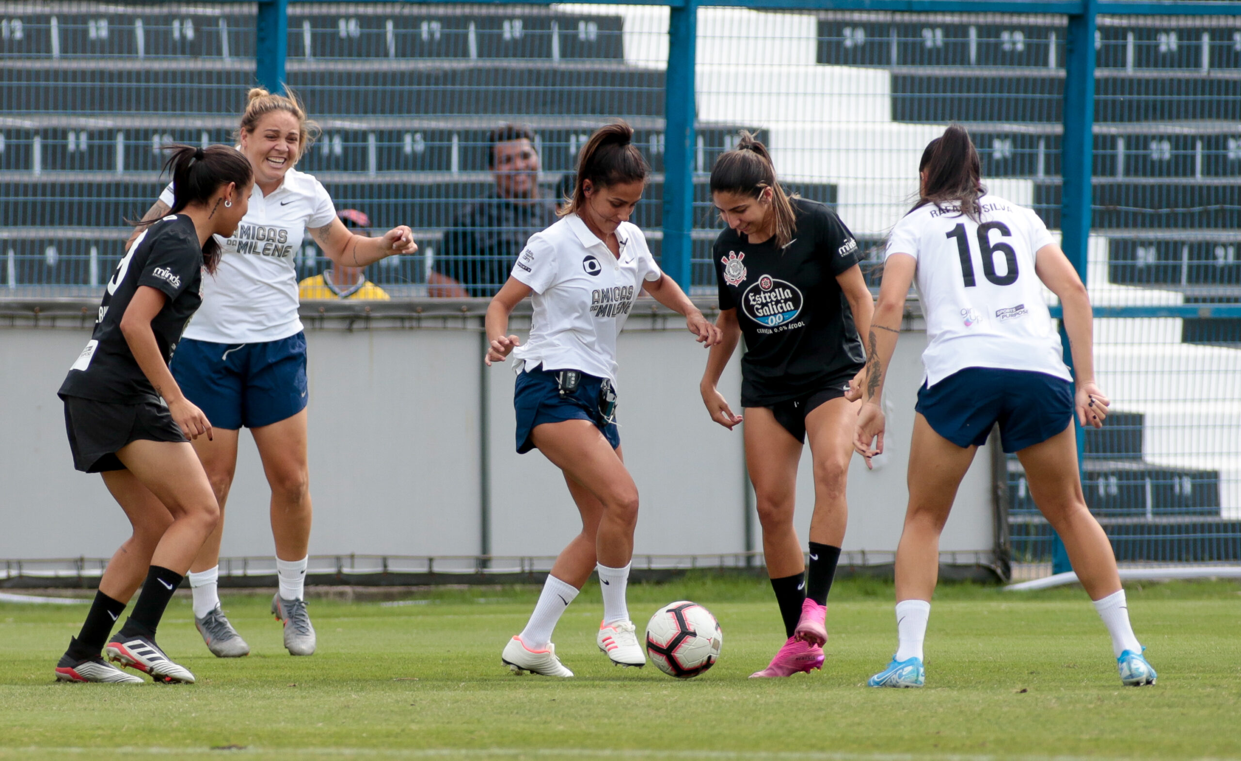 Four women playing soccer and smiling