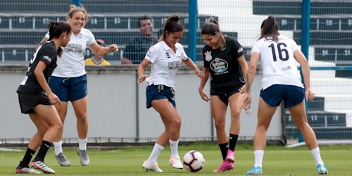 Four women playing soccer and smiling